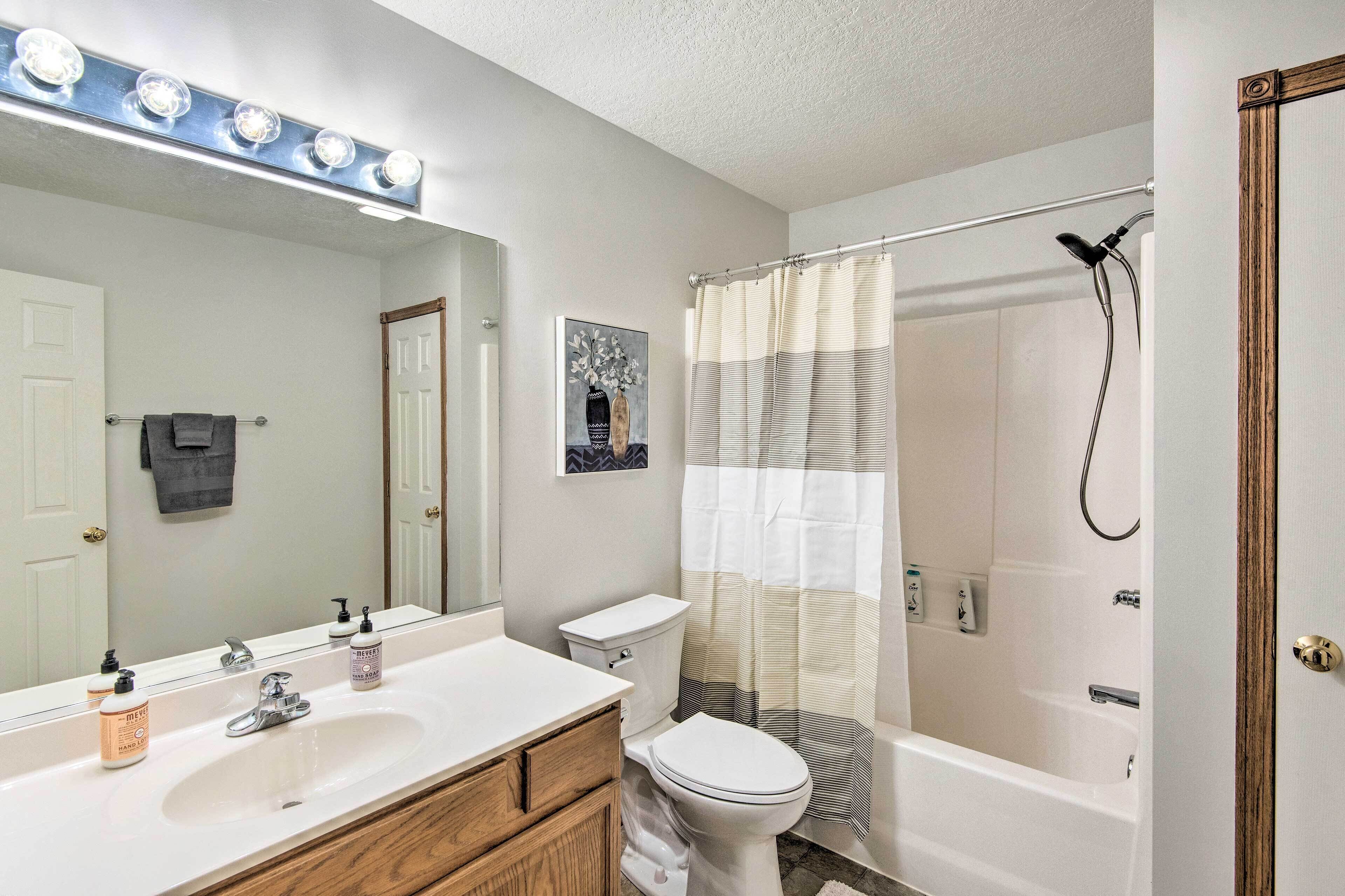 A bathroom with a large mirror, vanity, toilet, and a shower area.