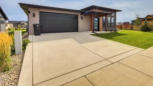 A modern residential house with a large garage, a well-maintained lawn, and a clear sky. - Stylish Montana Vacation Rental w/ Private Hot Tub (Red Lodge)