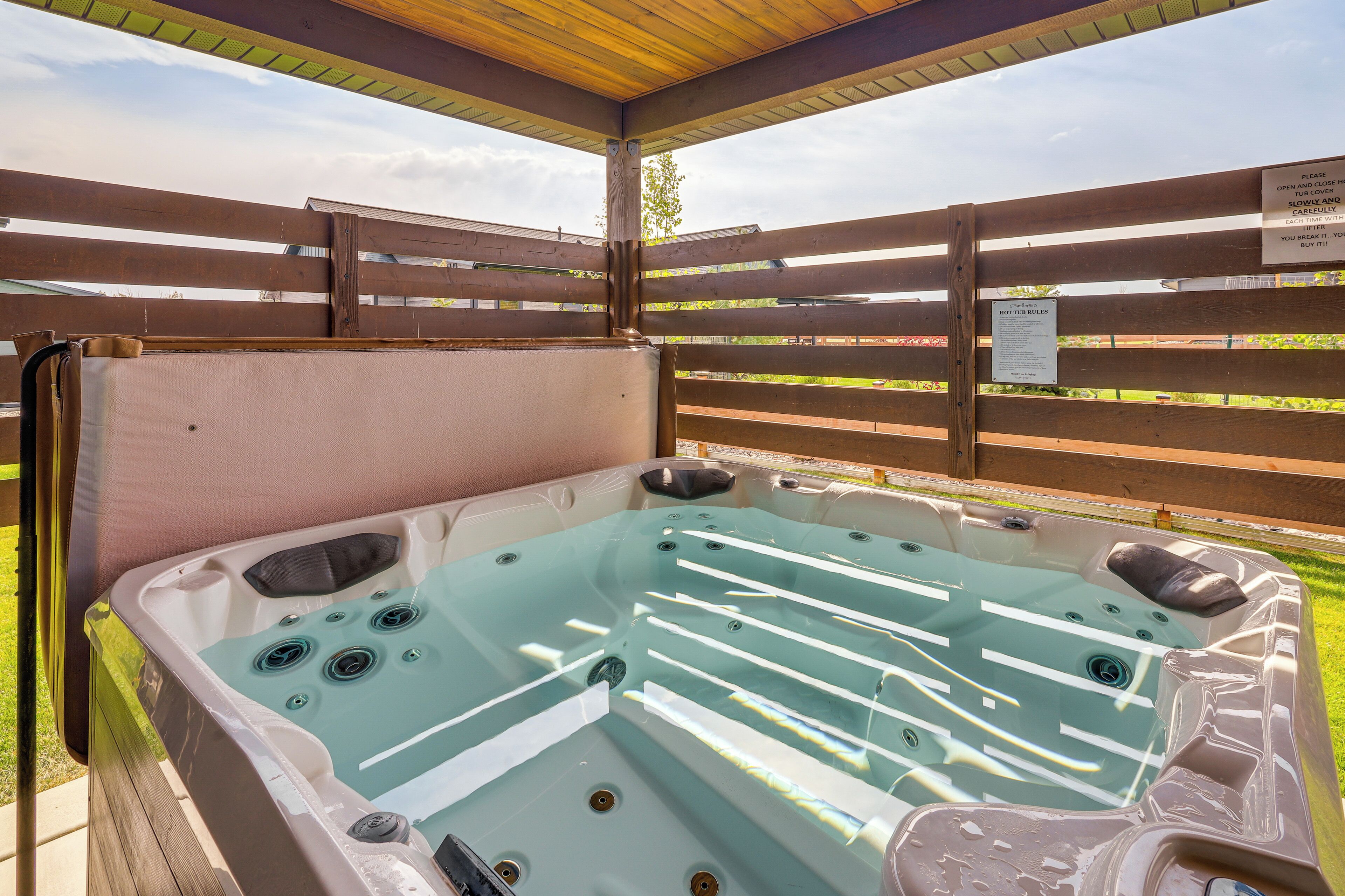 A hot tub with a wooden deck and a sign with instructions.