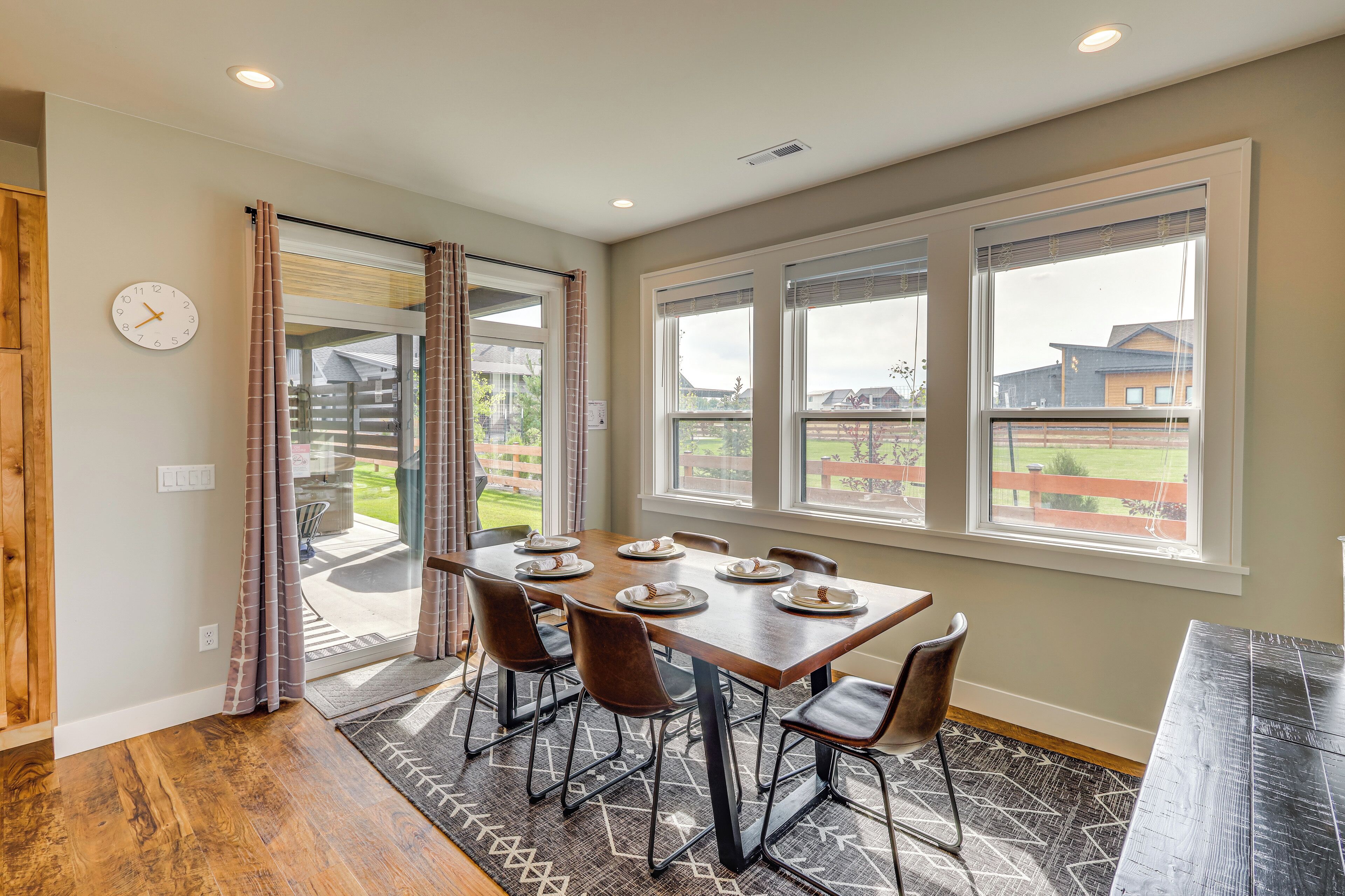 A dining area with a table set for six, large windows, and a view of the outside.