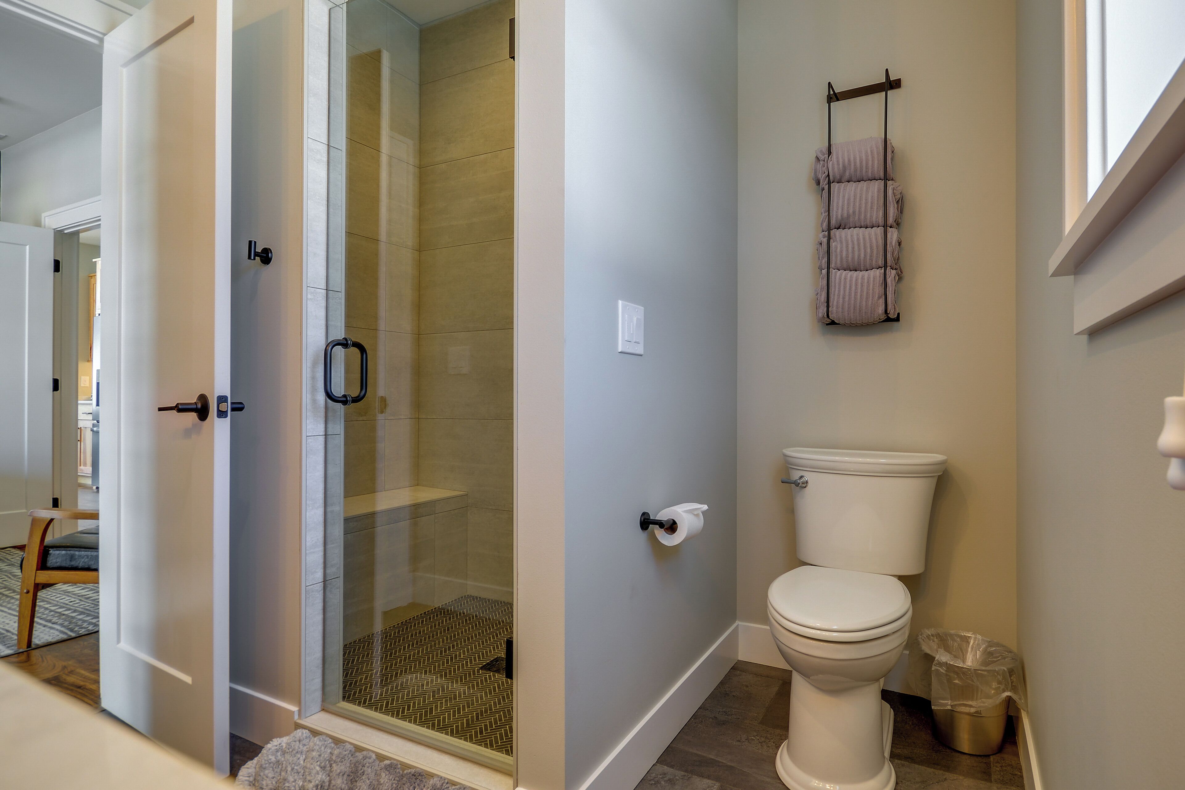 A bathroom with a glass-enclosed shower, a toilet, and a towel rack.