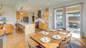 A modern kitchen with wooden cabinets, a central island, and a dining area with a wooden table set for four. - Stylish Montana Vacation Rental w/ Private Hot Tub (Red Lodge)