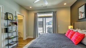 A bedroom with a large bed, a bookshelf, and a view through a sliding door. - Stylish Montana Vacation Rental w/ Private Hot Tub (Red Lodge)