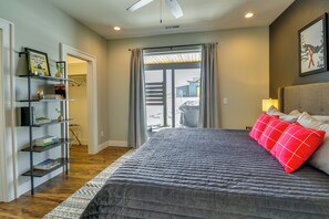 A bedroom with a large bed, a bookshelf, and a view through a sliding door. - Stylish Montana Vacation Rental w/ Private Hot Tub (Red Lodge)