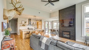 A modern living room with a large gray sectional sofa, a fireplace, and a mounted deer head. - Stylish Montana Vacation Rental w/ Private Hot Tub (Red Lodge)