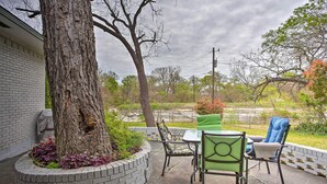 A patio area with a brick planter, a table, and two chairs. - 8 Mi to Lake Ray Hubbard: Creekside Garland Home (Garland)