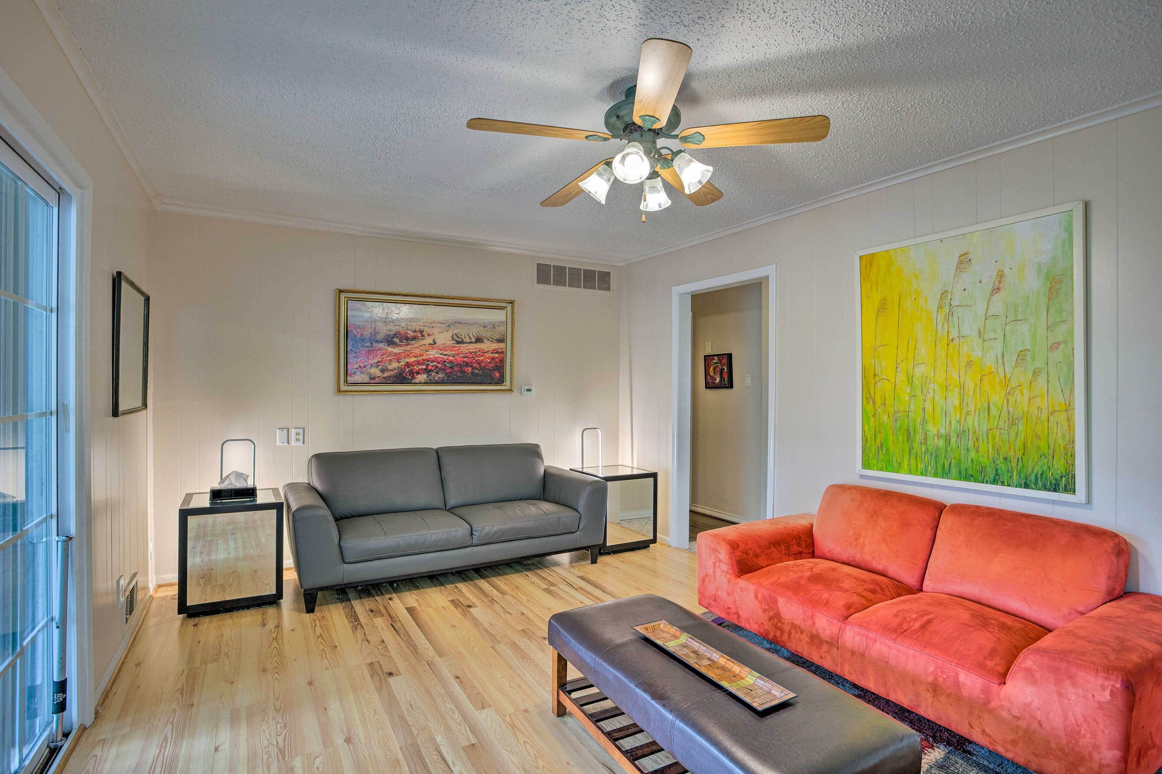 A living room with a grey sofa, an orange sofa, a coffee table, a ceiling fan, and two side tables.