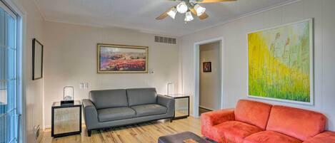 A living room with a grey sofa, an orange sofa, a coffee table, a ceiling fan, and two side tables.