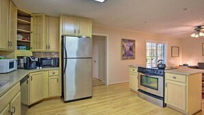 A compact kitchen with wooden cabinets, a stainless steel refrigerator, a microwave, a coffee maker, and a stove. - 8 Mi to Lake Ray Hubbard: Creekside Garland Home (Garland)