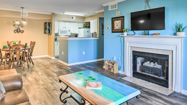 A living room with a fireplace, a television mounted above it, and a dining area with wooden furniture.