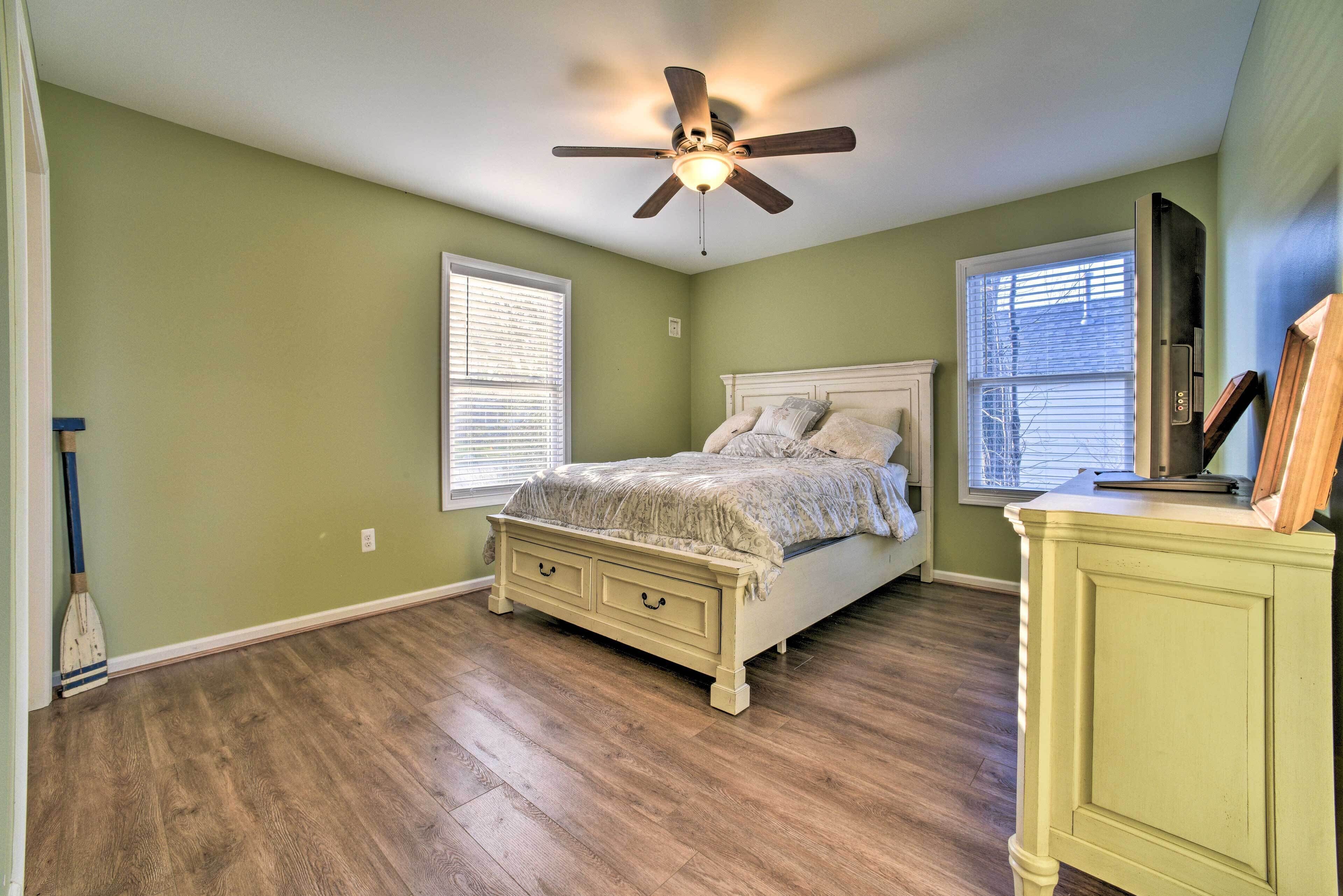 A bedroom with a bed, a ceiling fan, and a dresser.