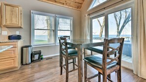Une cuisine avec des meubles de rangement en bois, une poubelle en acier inoxydable et une table à manger avec des chaises.