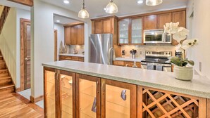A kitchen with wooden cabinets, a stainless steel refrigerator, a microwave, and a stove. There are pendant lights above the counter. - Peaceful Edwards Condo w/ Mountain Views! (Edwards)
