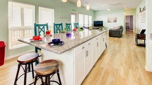 Una cocina amplia con una isla grande, taburetes de bar y un comedor con sillas.
