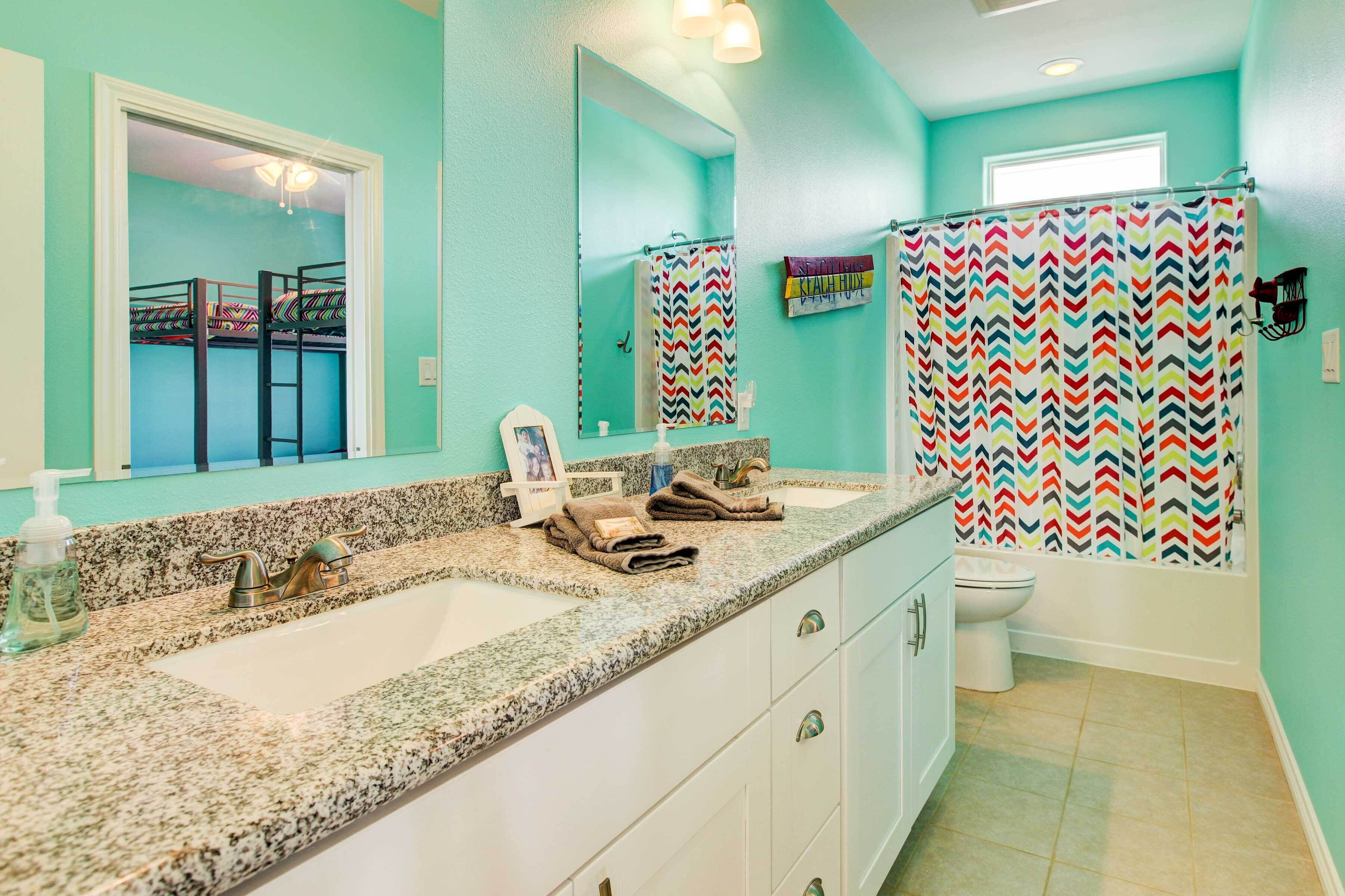 Une salle de bain avec deux lavabos, un miroir, des toilettes et un rideau de douche à motifs en zigzag.