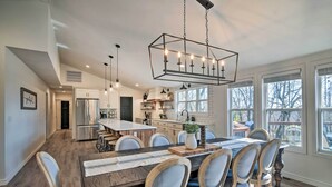 A spacious kitchen with a central island, wooden dining table, and chairs. - 'the Retreat on Reno' Home w/ Hot Tub + Deck! (Reeds Spring)