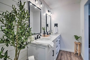 A modern bathroom with a white vanity, black fixtures, and a large mirror.