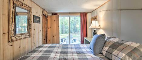 Une chambre avec un grand lit, des murs en bois, une fenêtre et une vue sur l’extérieur.