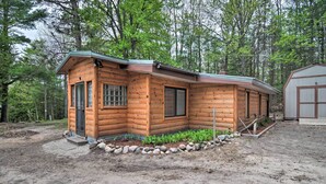 Une cabane en bois avec une véranda, un petit abri de jardin et une bordure en pierres.