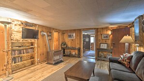 Un intérieur chaleureux avec des boiseries, un canapé, une table basse, une bibliothèque, un téléviseur et une cheminée.