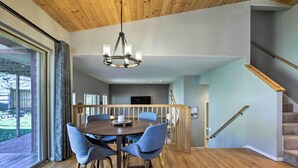 A dining area with a wooden table and chairs, a chandelier, and a view of the outdoors. - Cozy Carbondale Escape w/ Deck & Grill! (Carbondale)