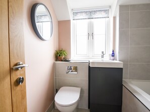 A bathroom with a toilet, sink, and mirror. - Conybeare Cottage (Lyme Regis)
