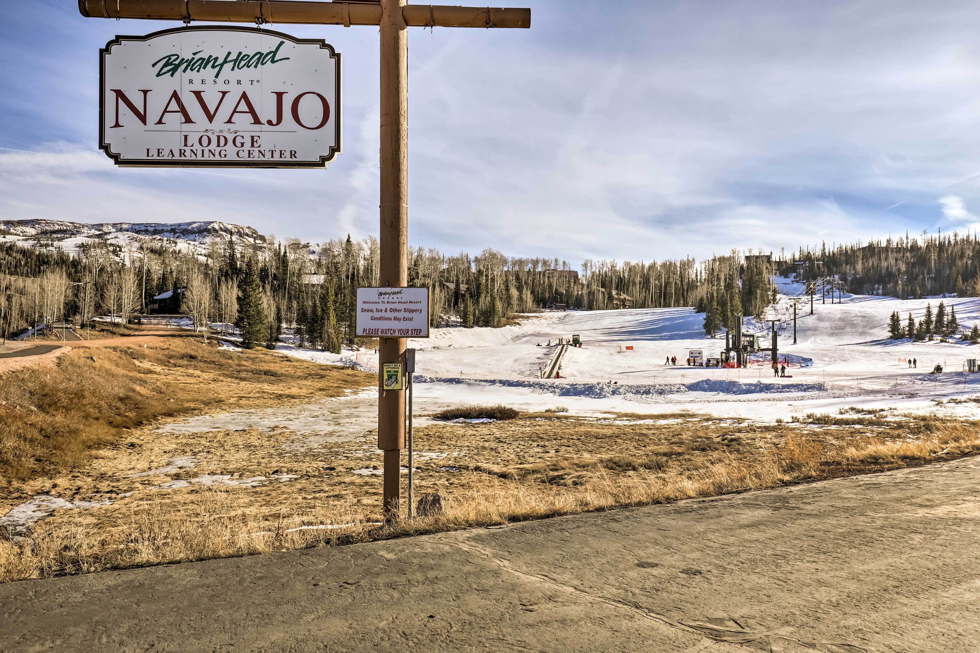 A sign for Brian Head Resort Navajo Lodge Learning Center with a warning about slippery conditions.