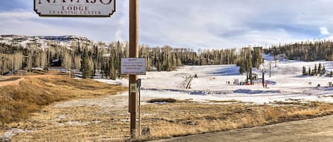 Señal para el Centro de Aprendizaje Navajo Lodge de Brian Head Resort, con advertencia sobre condiciones resbaladizas.