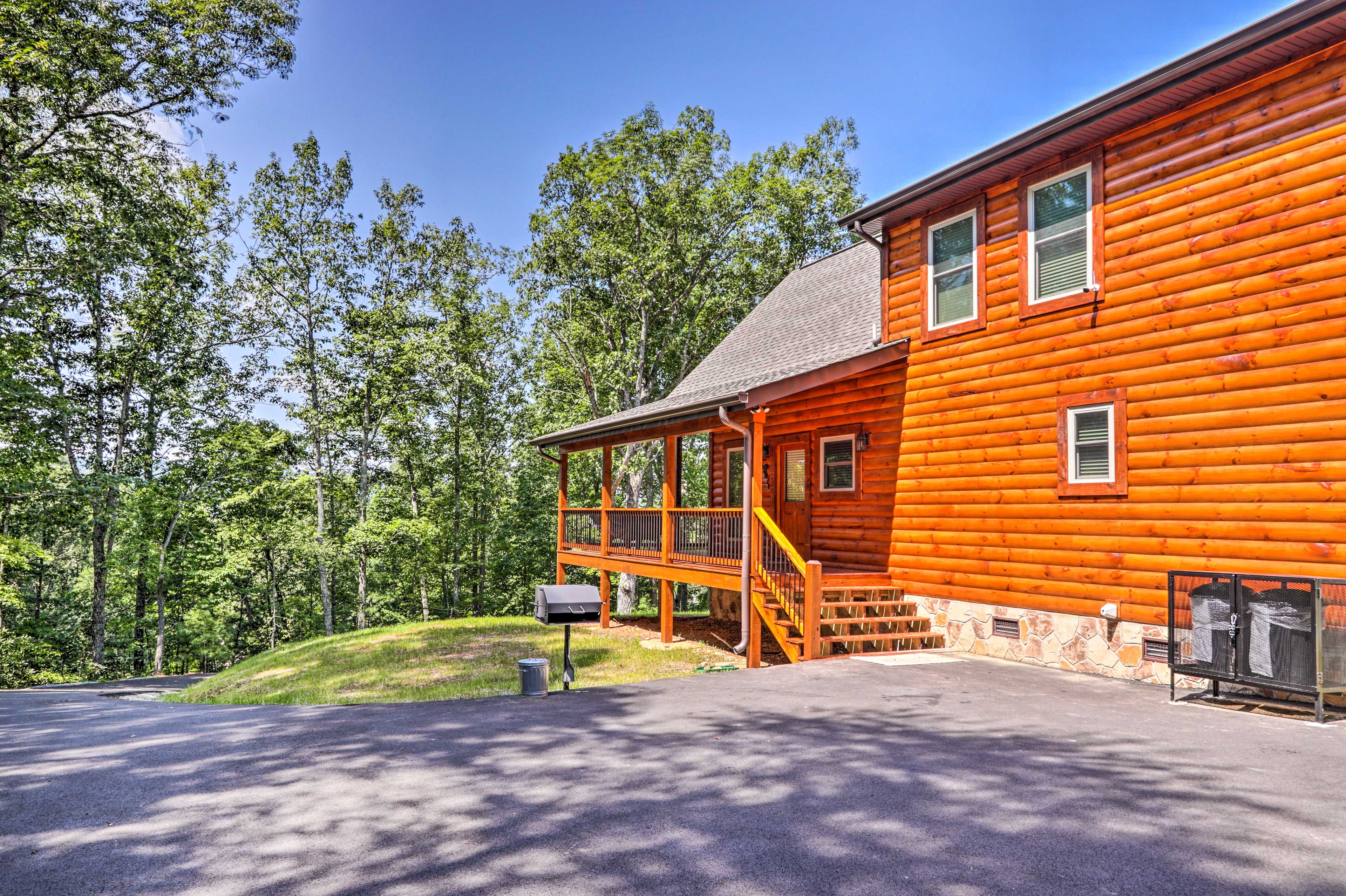 A log cabin with a porch, a mailbox, and a stone foundation.