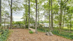 A park with a wooden deck, benches, and a dirt path surrounded by trees.