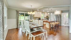 A spacious kitchen with wooden flooring, white cabinetry, and a dining area with a table set for four.