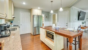 A modern kitchen with a wooden island, stainless steel appliances, and pendant lighting.