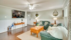 A living room with a green sofa, wooden coffee table, and a ceiling fan.