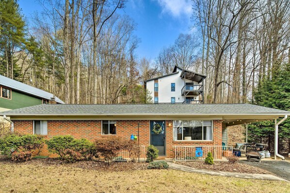 A two-story house with a brick facade, a covered porch, and a small front yard.