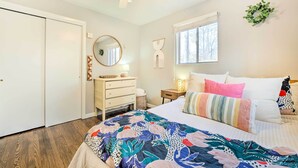 Un dormitorio con cama, cómoda, espejo y ventana.