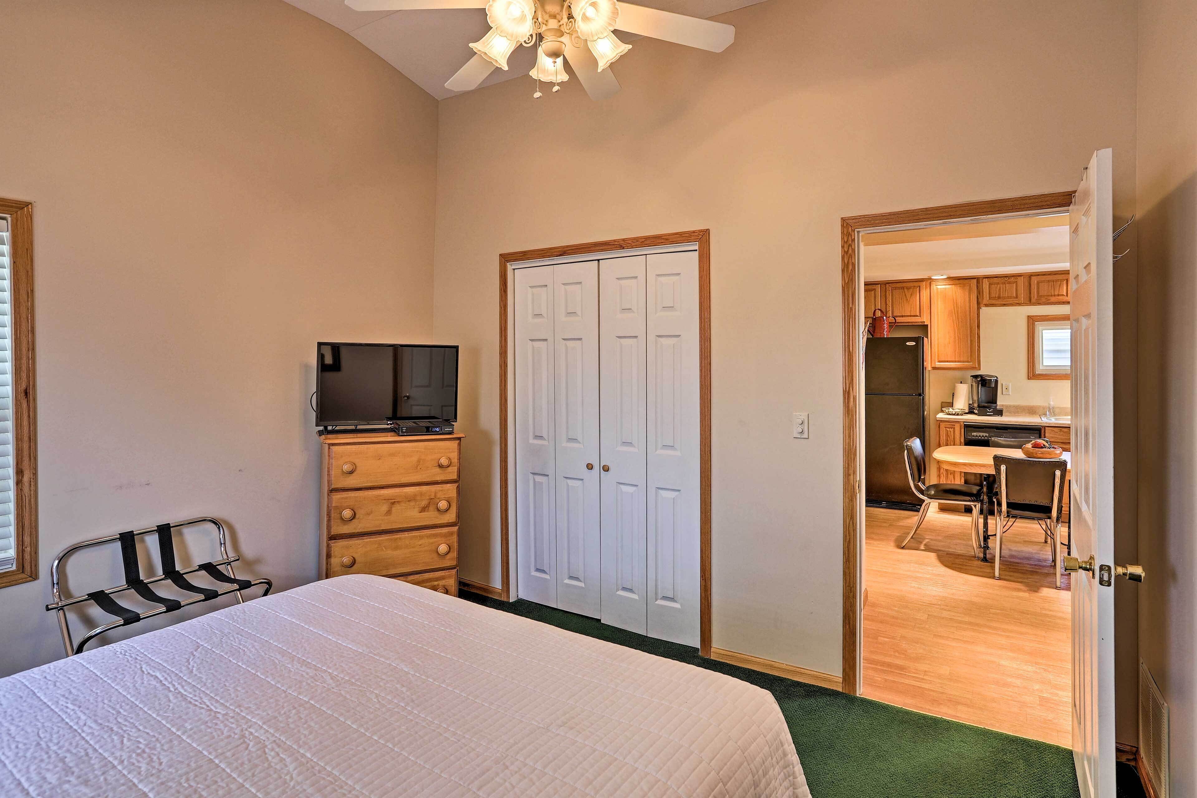 A bedroom with a bed, a dresser, a TV, and a closet.