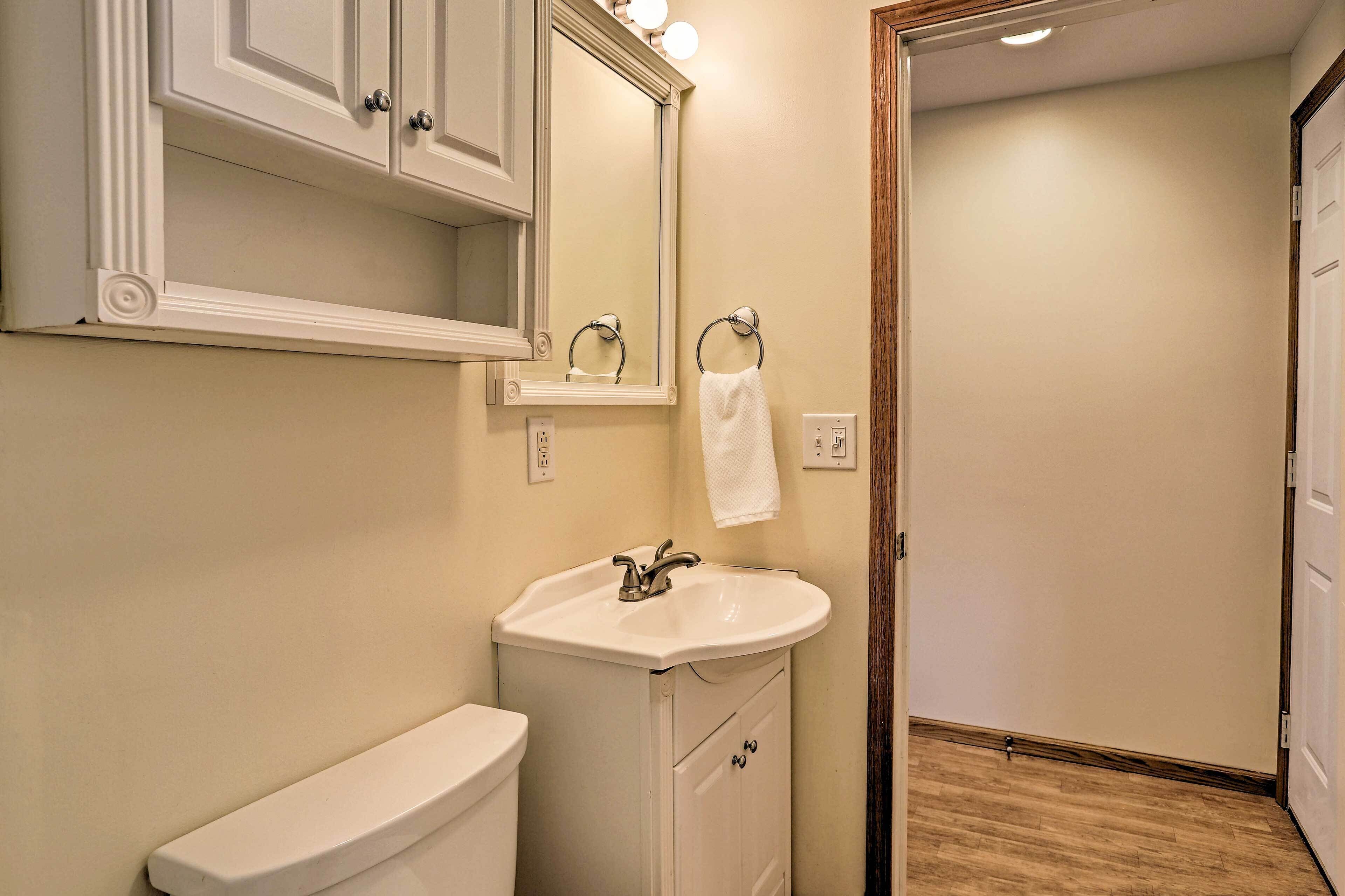 A bathroom with a white sink, a toilet, a mirror, and a towel ring.