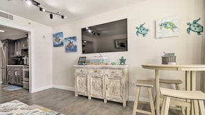 A modern kitchen with stainless steel appliances, a white cabinet with a turtle-themed design, and a flat-screen TV mounted on the wall. - Oceanfront Resort Condo in North Myrtle Beach (North Myrtle Beach)