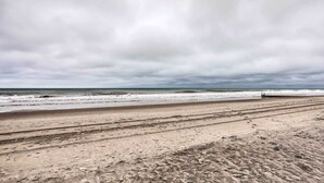 A beach with a wide sandy area and a person standing near the water's edge. - Oceanfront Resort Condo in North Myrtle Beach (North Myrtle Beach)