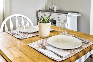 A dining table set with plates, cutlery, and glasses, a potted plant, and a white chair. - Pittsboro Studio ~ 20 Mi to Chapel Hill! (Pittsboro)