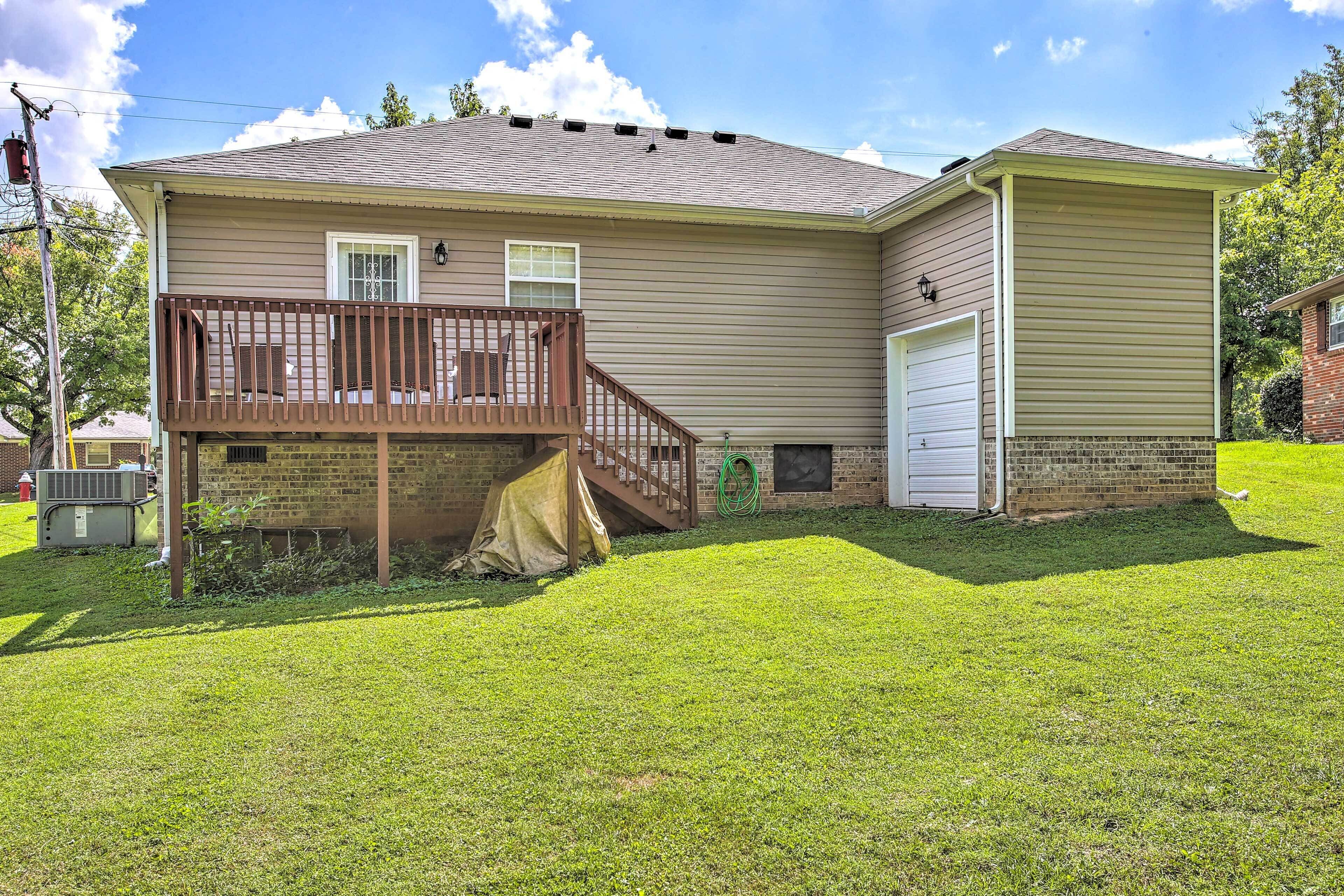 A two-story house with a covered deck, a garage, and a well-maintained lawn.