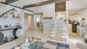 A spacious living area with a staircase, a kitchen in the background, and a dining area with a table and chairs.