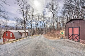 A gravel road leading to a red barn and a wooden shed. - Cabin Rental Near Pennsylvania State Parks (Blain)