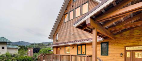 A wooden cabin with a porch, a staircase, and a mountain in the background.