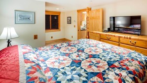 A bedroom with a large bed, a television, a wooden dresser, and a window with blinds. - Ketchikan Apt - Walk to Refuge Cove Beach! (Ketchikan)