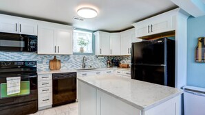 A modern kitchen with white cabinets, a black refrigerator, a microwave, and a dishwasher.