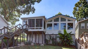 A two-story house with a covered patio and a wooden staircase leading to a deck.