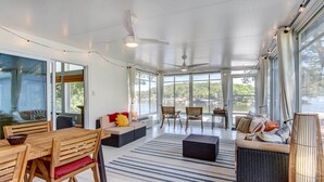 A spacious room with a dining area, seating, and large windows offering a view of the outdoors.