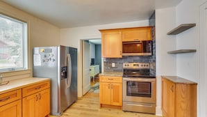 Una cucina con mobili in legno, elettrodomestici in acciaio inossidabile e una parete rivestita di piastrelle.