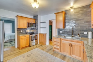 A modern kitchen with wooden cabinets, a granite countertop, and a built-in microwave.